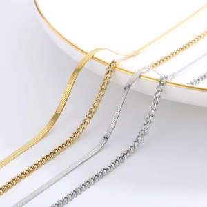 Close-up of gold and silver snake and Cuban chains on a white plate with gold trim