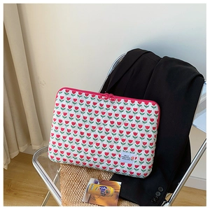 Quilted floral laptop sleeve with red tulips and pink zipper on a clear chair