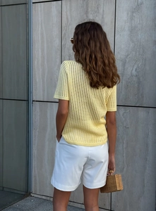 Detail of light yellow knit top showing intricate hollow out mesh and ribbed hem finish