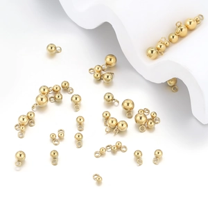 Golden round bead charms with loop for DIY jewelry making on white background
