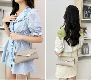Beige lychee texture baguette bag with golden chain and lock shown on a model