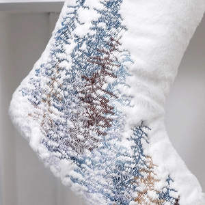 Detailed close-up of white plush Christmas stocking with snowflake tree embroidery pattern