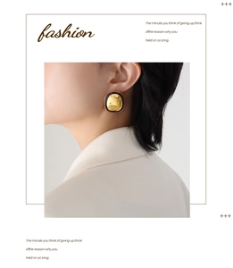Detail of vintage embossed gold earrings with black enamel border worn by model