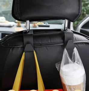 Detail of dual-sided black car headrest hook holding a paper bag and a coffee cup