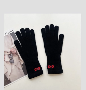 Detail of black knitted gloves featuring a red Hello Kitty bow embroidery detail