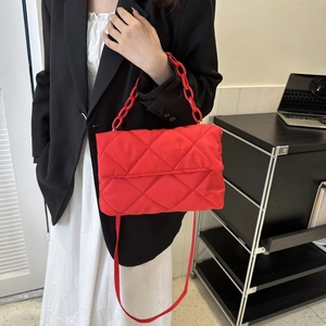 Close-up of quilted red shoulder bag featuring bold plastic chain and nylon texture