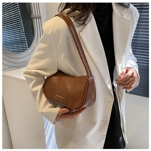 Brown retro underarm bag with gold FASHION & BAG logo shown in model's street style