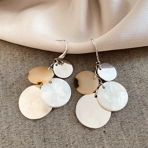 Close-up of geometric acrylic tassel earrings with marble resin disks and silver hooks