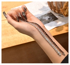 Detailaufnahme von zwei Tennisarmbändern mit weißen und bernsteinfarbenen Zirkonia