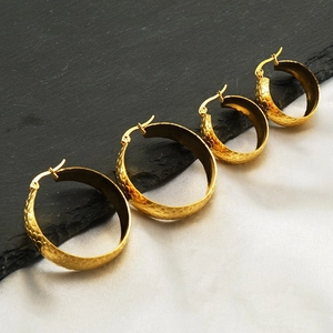 Lot de quatre boucles d'oreilles créoles dorées martelées de différentes tailles sur fond bicolore