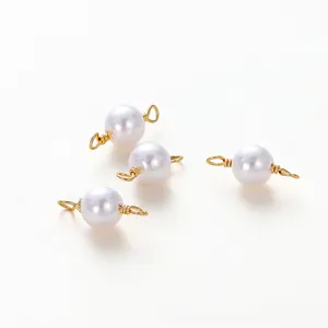 Detail of four white pearl connectors with gold-plated double loops for DIY jewelry making