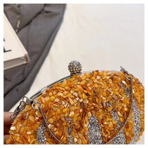 Close-up of orange gemstone shards and silver rhinestone strips on an evening clutch bag