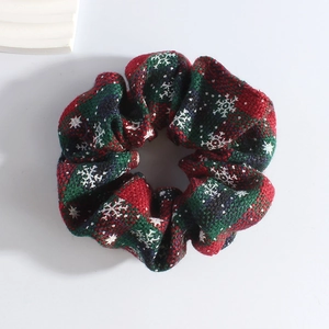 Detailed close-up of Christmas scrunchie with red and green plaid and snowflake pattern