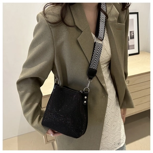 Detail of black rhinestone bucket bag with black and white herringbone woven strap