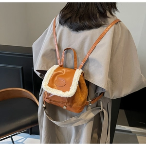 Detail of a vintage-style caramel PU leather mini backpack with cream faux fur trim and tag