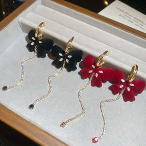 Detail shot of vintage red and black velvet bow tassel earrings in a wooden jewelry box