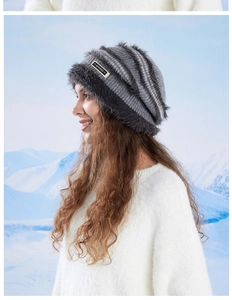 Detail of warm winter knit hat with fluffy faux fur trim against a snowy backdrop