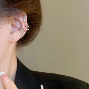 Macro view of silver snake-shaped ear cuff with sparkling zircon inlay on woman's ear