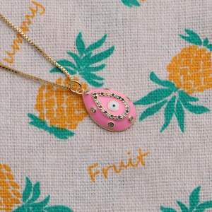 Detail of pink teardrop enamel pendant with evil eye design and colored zircons