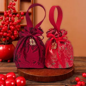 Detailed view of red brocade wedding favor bags with gold Double Happiness charms