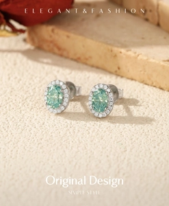 Macro detail of oval mint green moissanite earrings with halo diamonds on stone texture