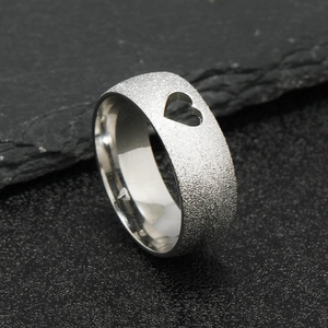 Macro detail of silver frosted stainless steel ring featuring heart cutout on the band