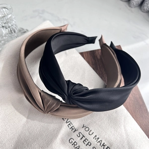 Close-up of elegant black and khaki knotted headbands on premium fabric background