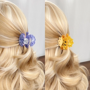 Floral shell and cute animal vinegar acid hair claws shown on golden curly hair