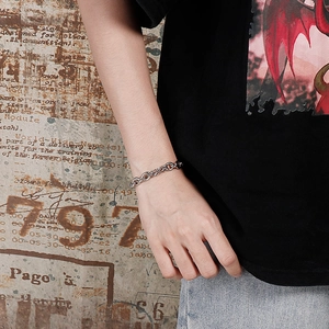 Close-up of a stainless steel dragon scale chain bracelet worn on a wrist in street style