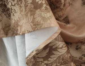 Detailed close-up of vintage floral satin fabric hem with high-quality stitching