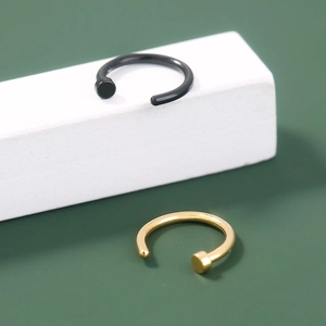 Gedetailleerde close-up van minimalistische zwarte en gouden piercingringen met gladde afwerking.