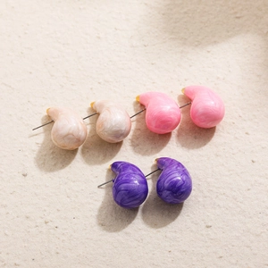 Colorful resin waterdrop earrings in pink, beige marble, and purple on a textured surface