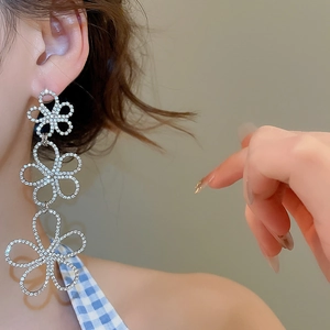 Detailed view of silver flower tassel earrings with crystals on a female model