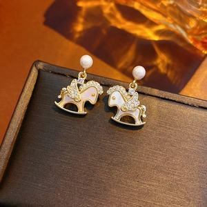 Detailed macro view of 14k gold plated rocking horse earrings with zircon and pearls