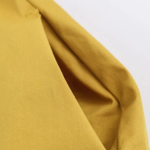 Gros plan sur le tissu popeline jaune gingembre avec texture sergé et détails de couture