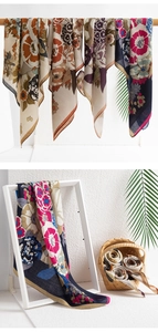 Selection of geometric floral print silk scarves displayed on a wooden rack and in a basket