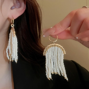 Détail des boucles d'oreilles à franges de perles avec cadre doré et pompons élégants