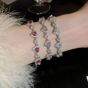 Close-up of heart-shaped zircon bracelets in pink, red, and clear on model wrist