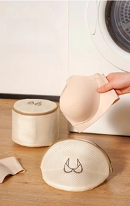 Close-up of mesh laundry bag with bra embroidery in front of a washing machine
