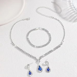 Détail d'une parure de bijoux argentés avec des pierres bleues en goutte et des strass