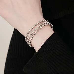 Bracciale rigido argento a tre strati di sfere indossato su un maglione nero chic