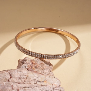 Detail of rose gold double-row diamond bracelet resting on natural stone with fine zircons