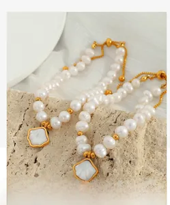 Detail of natural freshwater pearl bracelet with golden beads and shell charm on silk