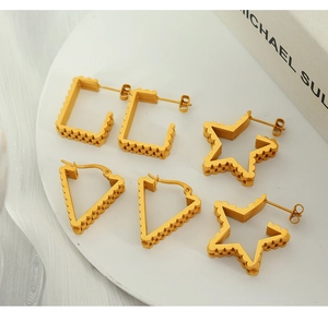 Detailed view of gold geometric earrings with textured edges on white porcelain plate