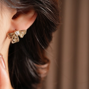 Détail de boucles d'oreilles nœud dorées avec zircons portées par un mannequin