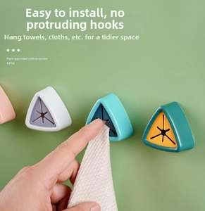 Detail of hand inserting a cloth into the triangular wall-mounted silicone towel holder