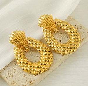 Macro shot of 18K gold plated geometric oval earrings with vintage texture on silk fabric