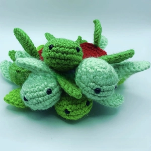 Detail of stacked handmade crochet turtle coasters showing green woven patterns and red accents