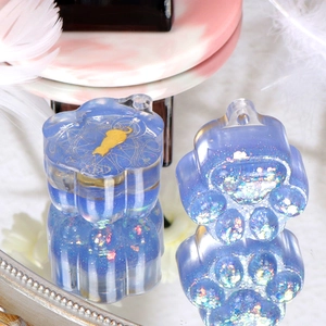 Detail of DIY cat paw resin charms with glitter and gold cat motifs on marble surface