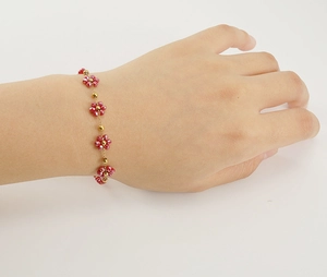 Detail of 18K gold stainless steel chain bracelet with red crystal flower charms
